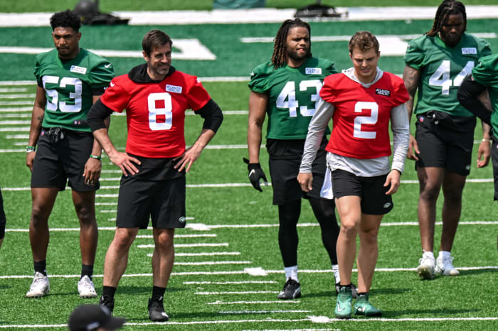 New York Jets quarterback Aaron Rodgers and quarterback Zach Wilson walk on the field at OTAs
